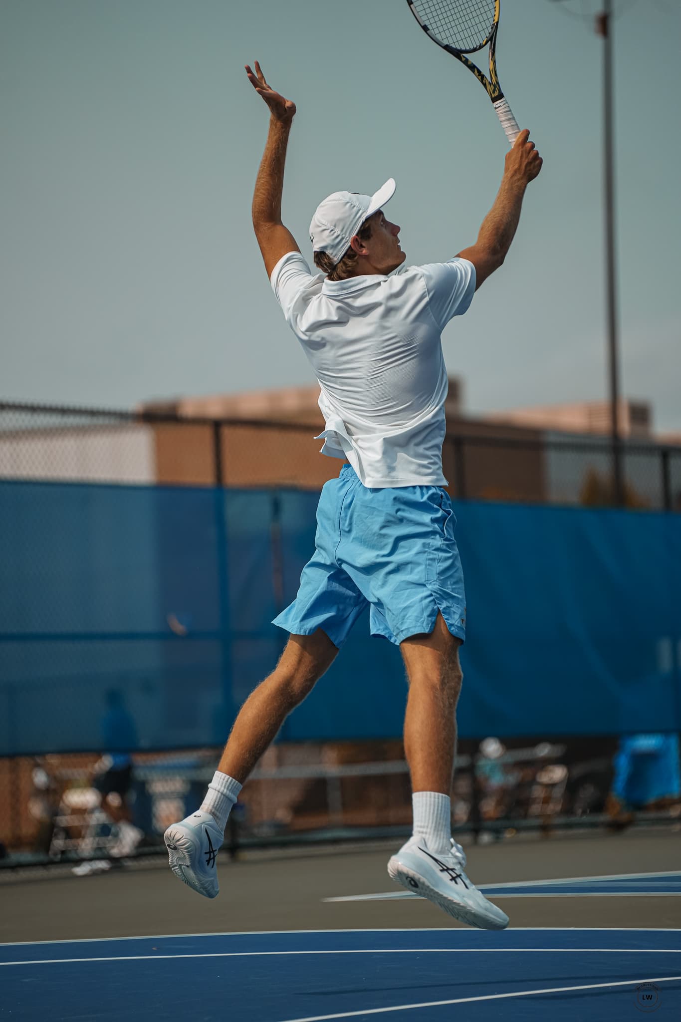 Alex Ganchev mid-serve on a blue hard court